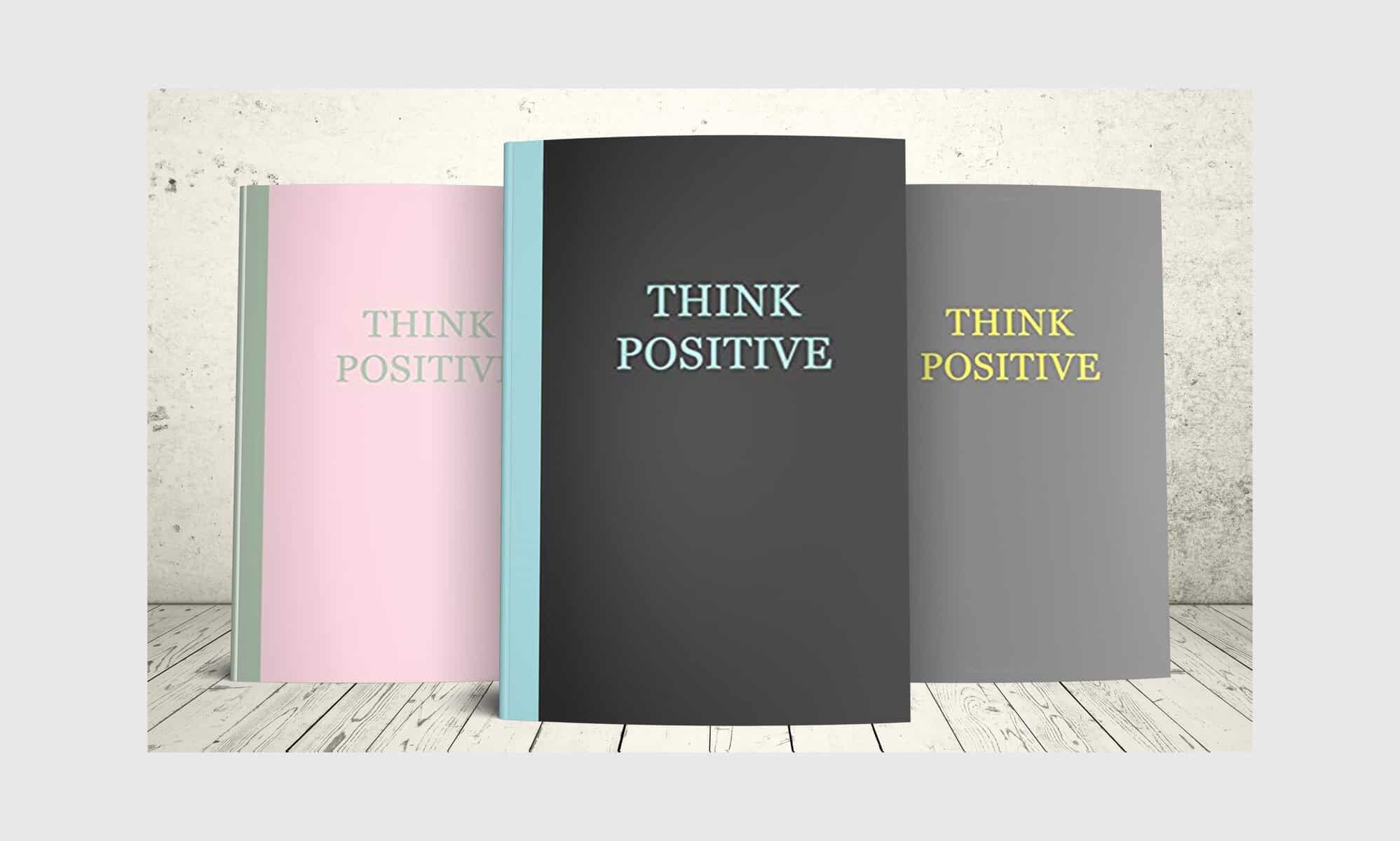 Think Positive Mockup size 5 with 3 Books Three journals from the motivational Think Positive series with text that says THINK POSITIVE: black cover with aqua blue text, grey cover with yellow text and light pink cover with sage green text.