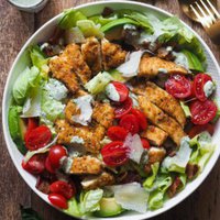 Crispy Chicken and Bacon Salad with Basil Tahini Dressing, an incredible salad that also makes a delicious meal. This salad combo is hard to beat and will make "Salad Meals" something to look forward to. The salad is placed in the middle of the shot, with a golden fork and a spoon on the top right corner and a little glass with extra dressing and a spoon in it on the top left corner.