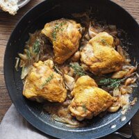 Jugoso Pollo al Cava (o Pollo al Champagne), sencillo, lleno de sabor y te hace quedar genial si tienes una comida con amigos o familia! Lleva cebolla y ajo, que quedan a punto de caramelo, y hierbas aromáticas para añadir un toque más de sabor. Es perfecto para hacer en modo batchcooking y así tener para más de un día. Y bueno, qué decir de las recetas de la abuela... ¡nunca fallan! Aquí el pollo se ve servido en una sartén profunda de hierro, con pan a un lado y un trapo en otro. El pollo está decorado con tomillo fresco.