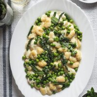Paula's Apron 10-Minute Creamy Gnocchi with Peas and Asparagus Spring on a plate with these 10-Minute Creamy Gnocchi with Peas and Asparagus. It's really that quick and so delicious! To speed things up I use pre-made gnocchi; then, there are bright peas and asparagus to make the most of seasonal ingredients. These are mixed with a creamy lemony garlicky white sauce that is to die for. And finally, some grated parmesan and mint leaves to top it all. | Paula's Apron Recipe