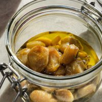 This Garlic Confit recipe is going to become your new pantry staple because it's so easy and confited garlic is so spectacular and versatile. You just need a few heads of garlic, your favourite spices and herbs, lots of olive oil and 30 minutes. The result is a scrumptious sort of sweet spreadable garlic that you can use in a thousand ways. As a bonus, you get garlic-infused oil! | Paula's Apron Recipe