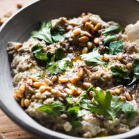 El Mutabal es un dip de berenjena muy parecido al Baba Ganoush con la gran diferencia de que el primero lleva tahini y no lleva melaza de granada. Es un aperitivo ideal o snack saludable, incluso va genial como acompañamiento. Es un dip cremoso, con un sabor meloso gracias a ese toque ahumado de la berenjena asada. Además es vegano (o se puede adaptar fácilmente), sin gluten y lo mejor, muy fácil de hacer. Acompáñalo de verduras o algún tipo de pan plano y listos, ya solo queda disfrutarlo. | Receta de Paula's Apron