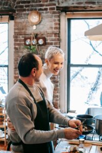 Celebrate Pride Month with These 9 Fabulous Date Night Ideas for the LGBTQIA+ Community 15 happy couple cooking dinner together in kitchen
