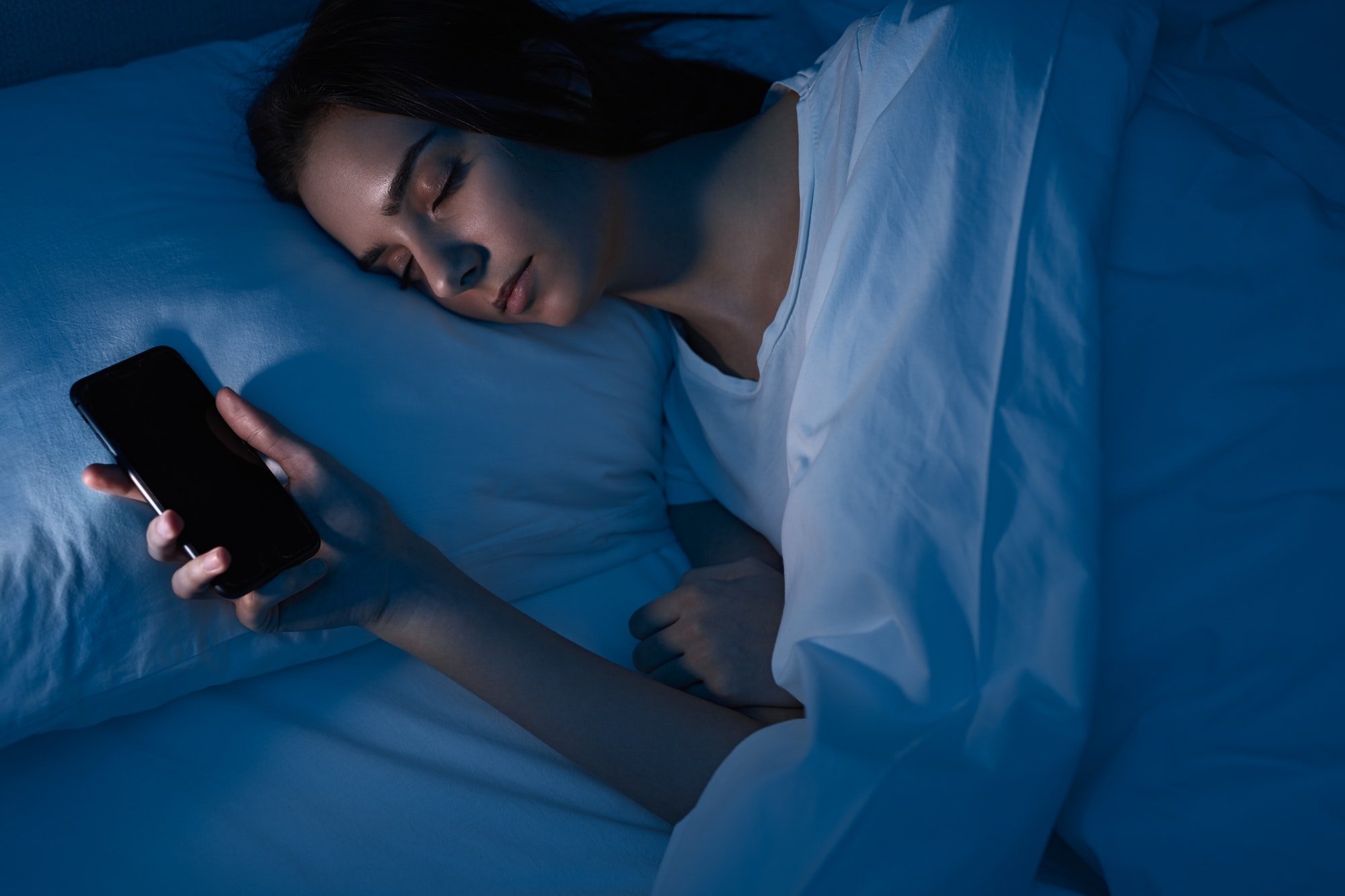 Woman sleeping with smartphone in bed Woman sleeping with smartphone in bed