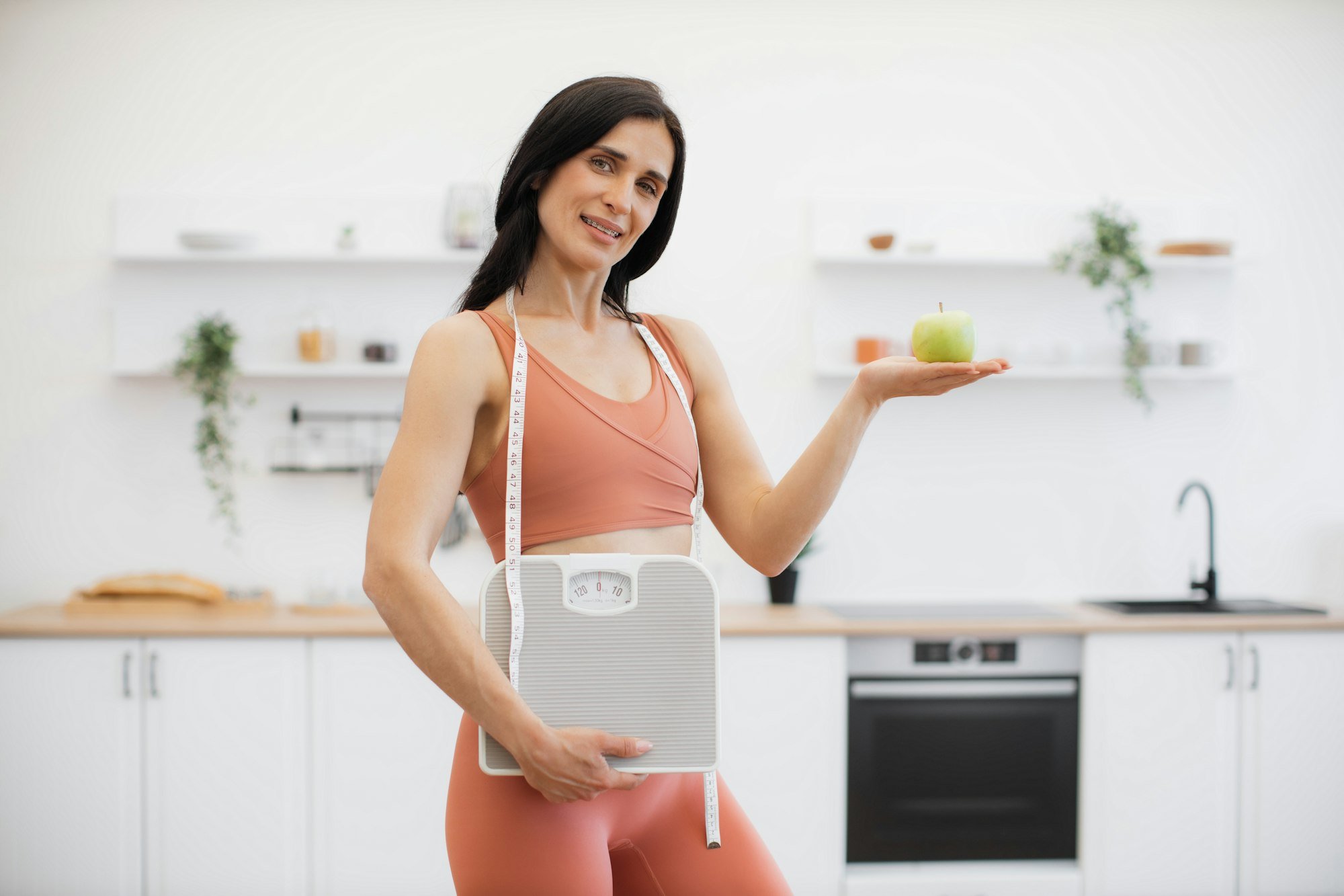 Health coach with measuring tape, scales and apple at home