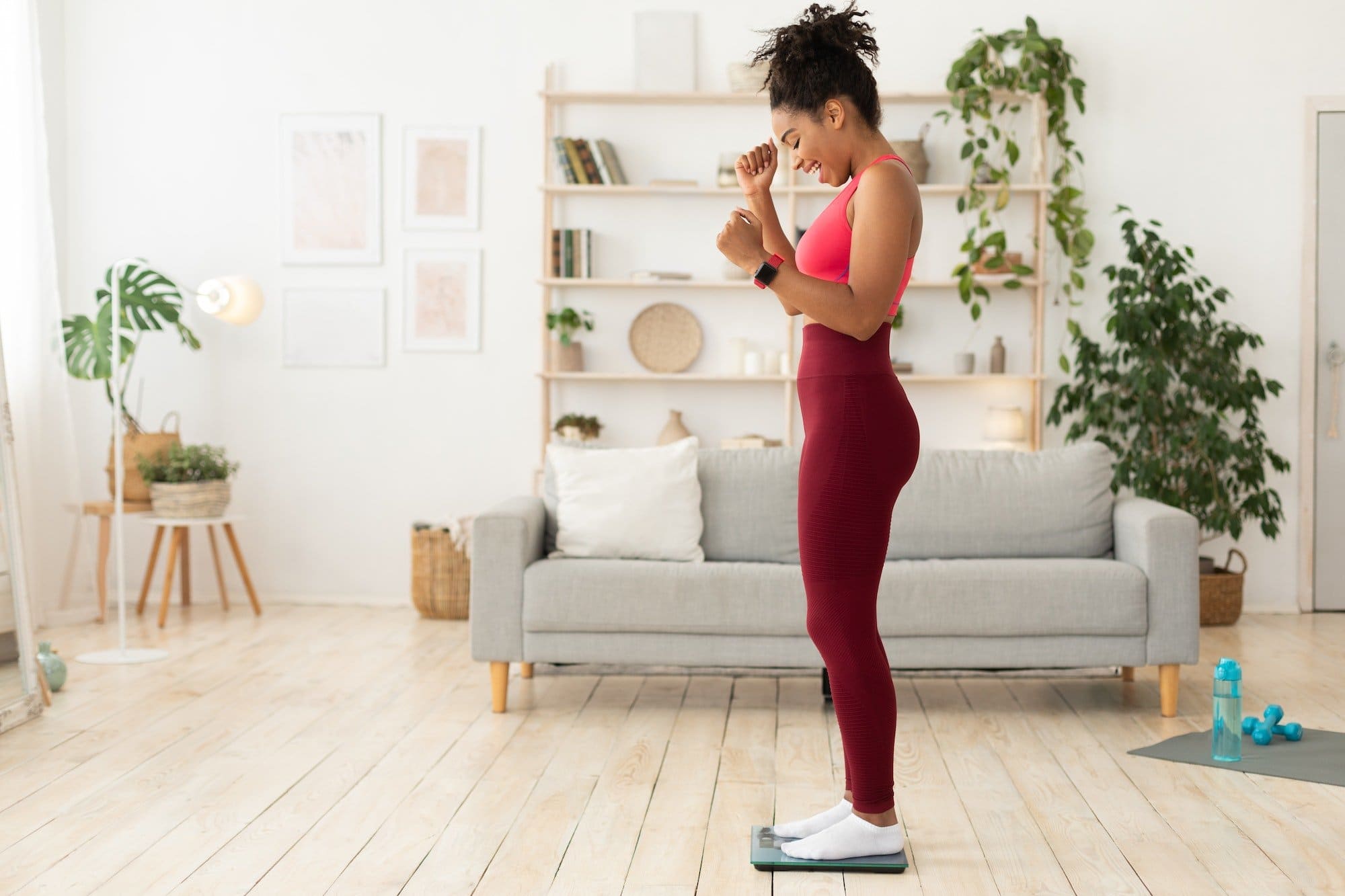 Joyful Black Woman Weighing Herself After Successful Weight Loss Indoors