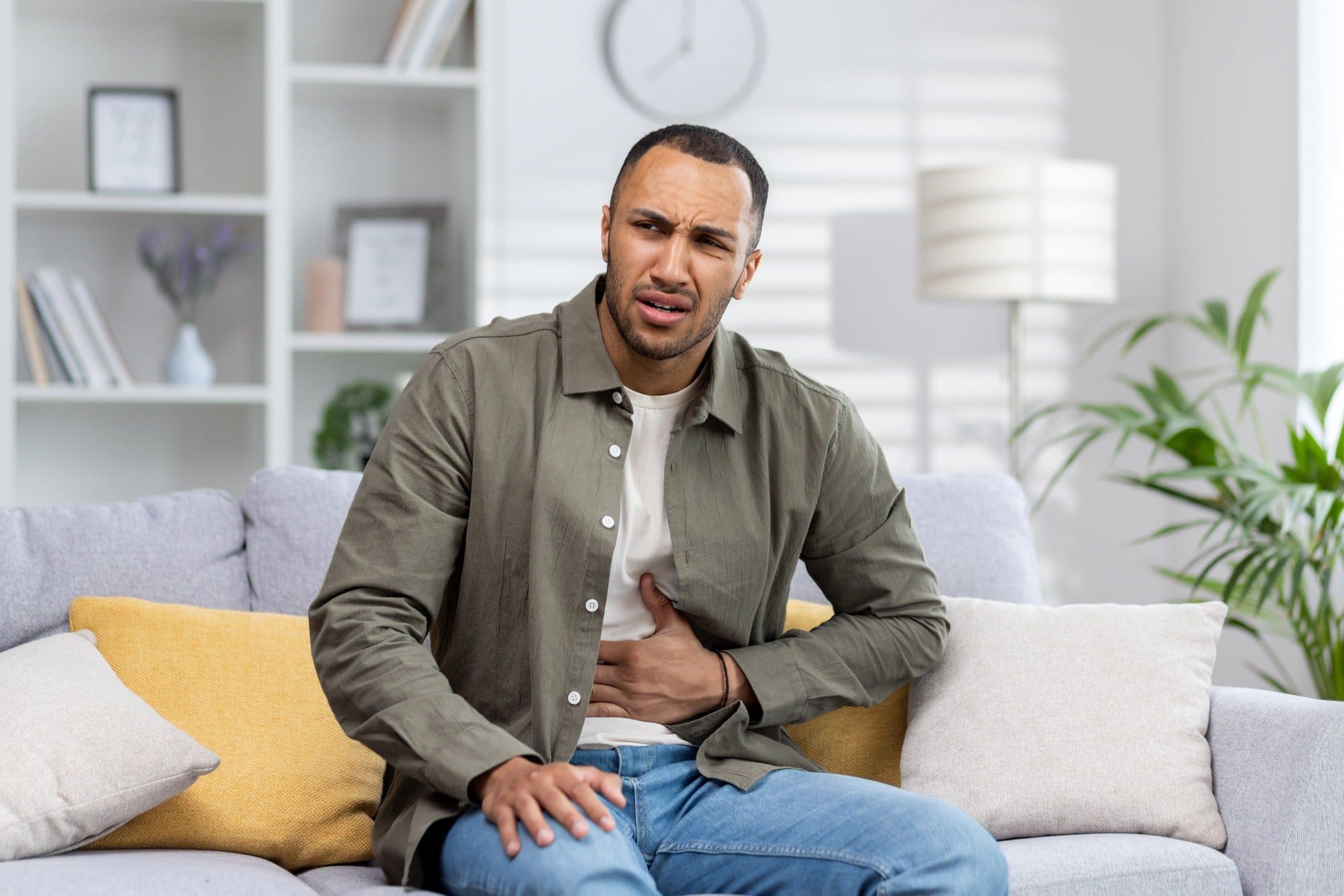 A young African American man is suffering from abdominal pain, stomach cramps and constipation. He