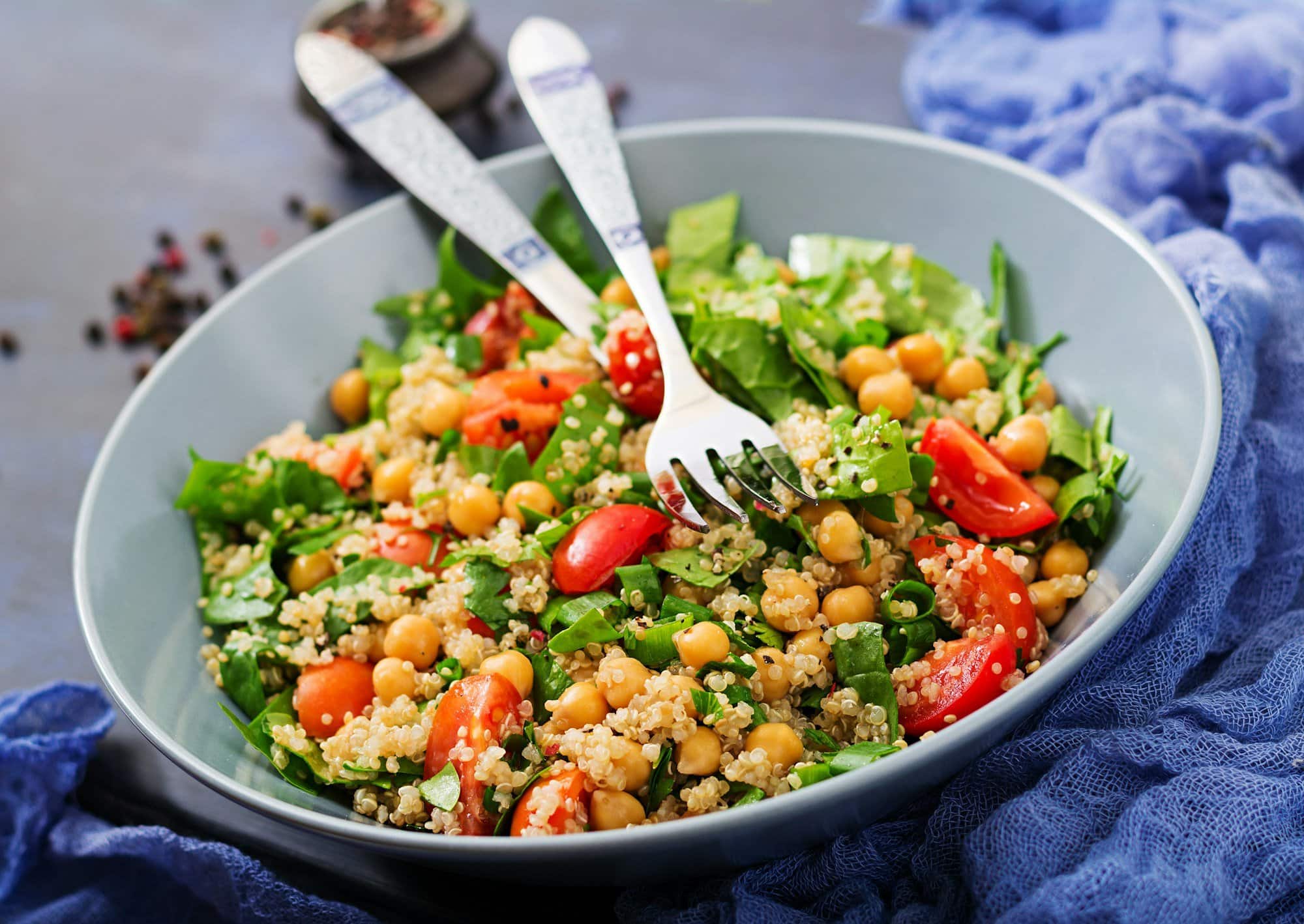Healthy vegan salad of fresh vegetables - tomatoes, chickpeas, spinach and quinoa