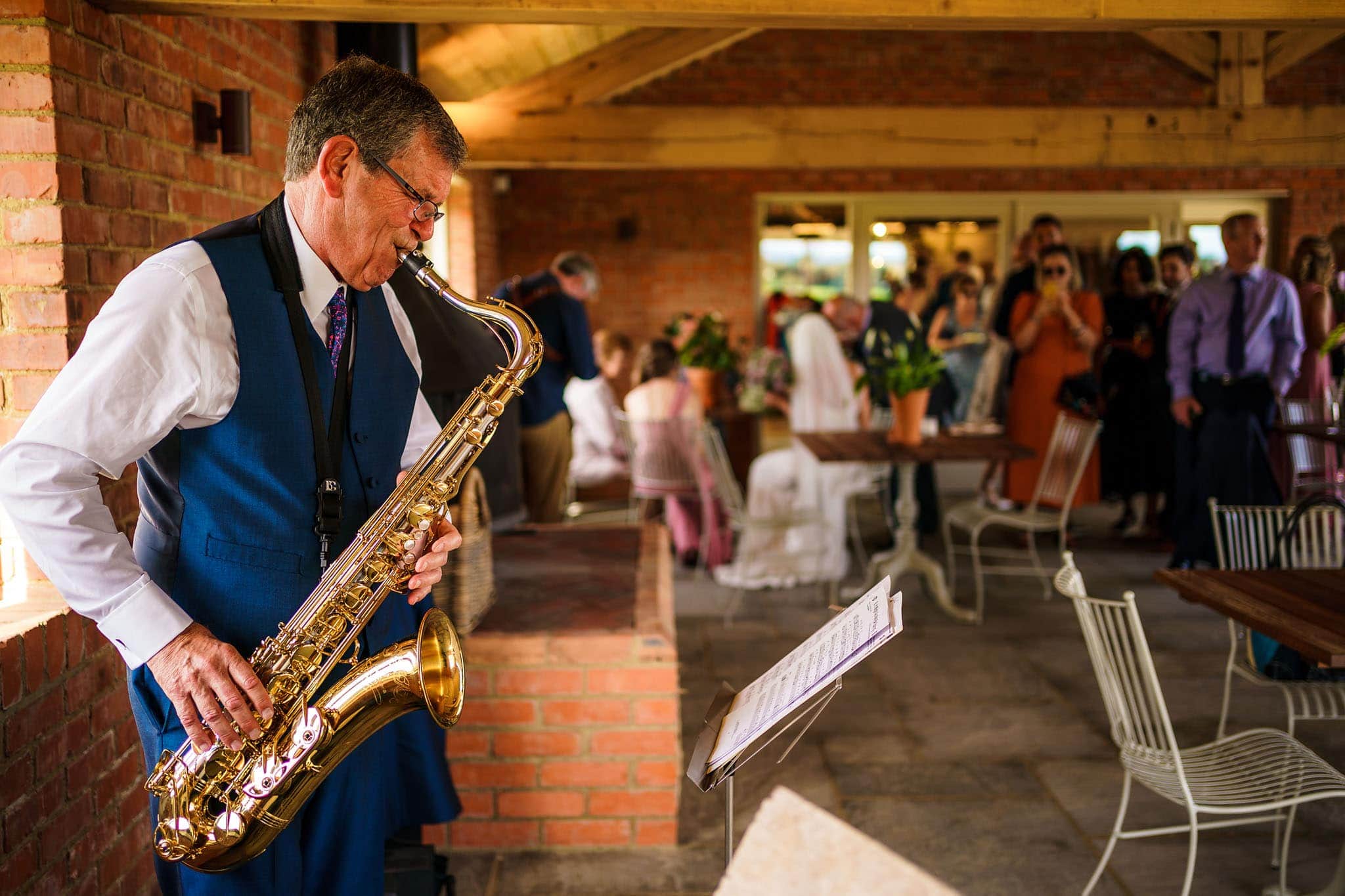 father of the bride playing his sax during the drinks reception