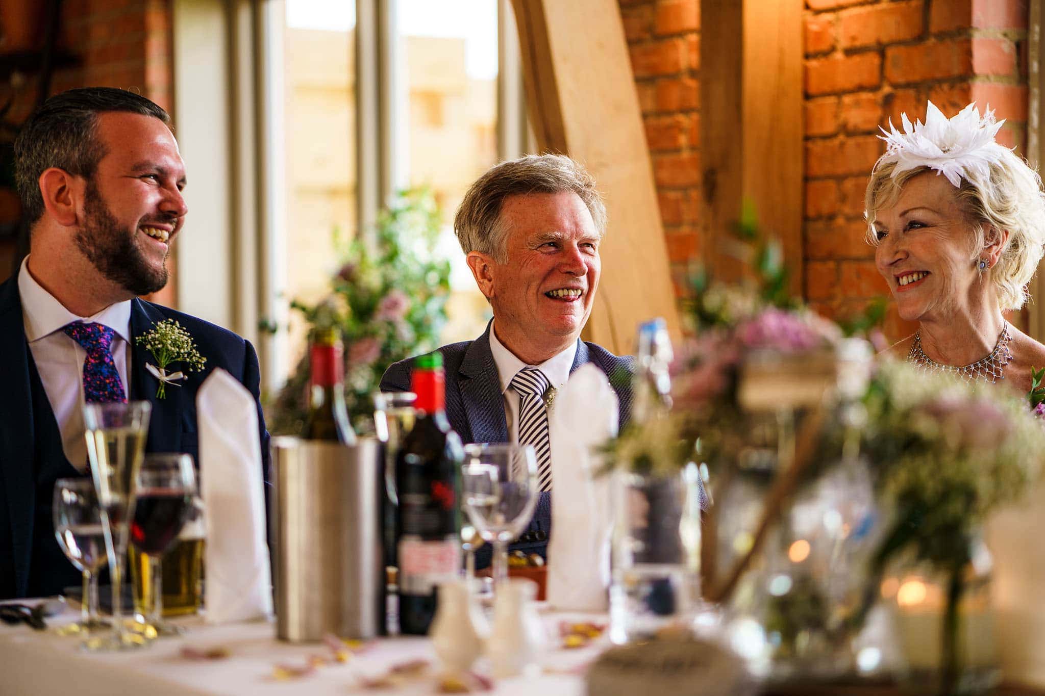 best man and the groom's parents laughing during the speeches