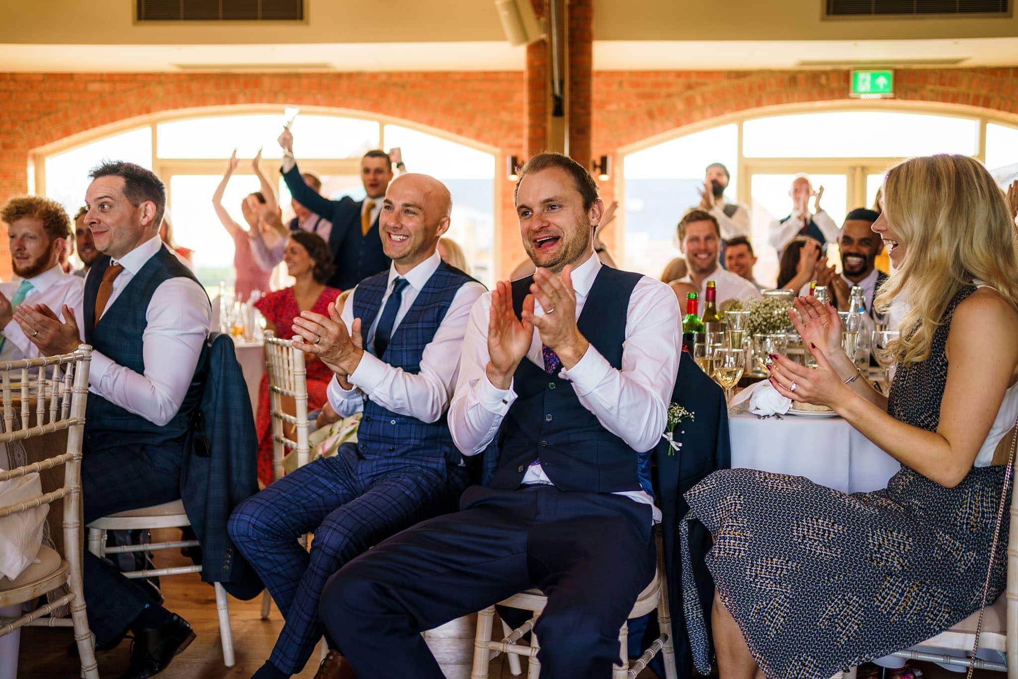 wedding guests clap and cheer during the speeches