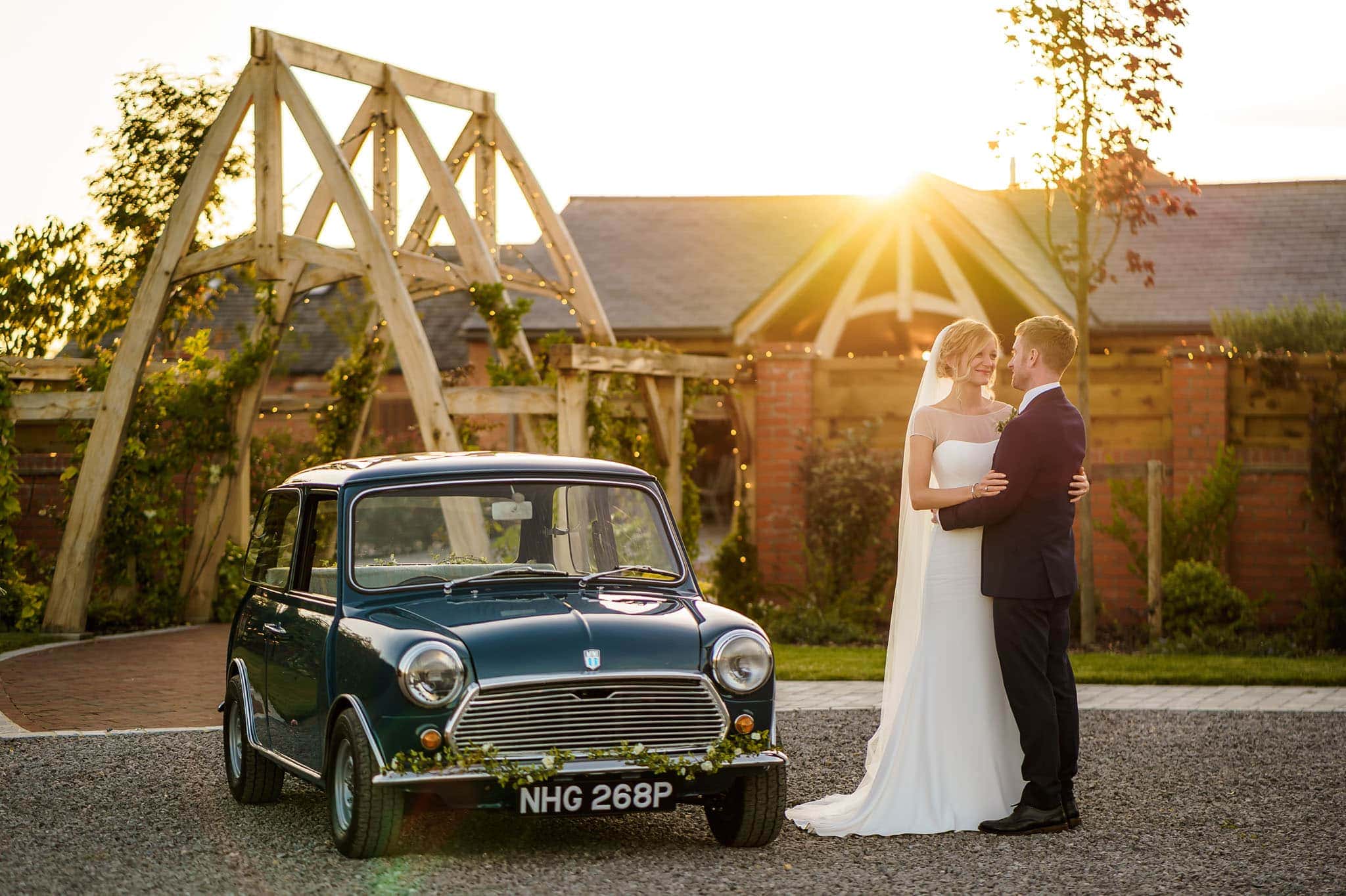 bride and groom with their Mini outside Cider Mill Barns