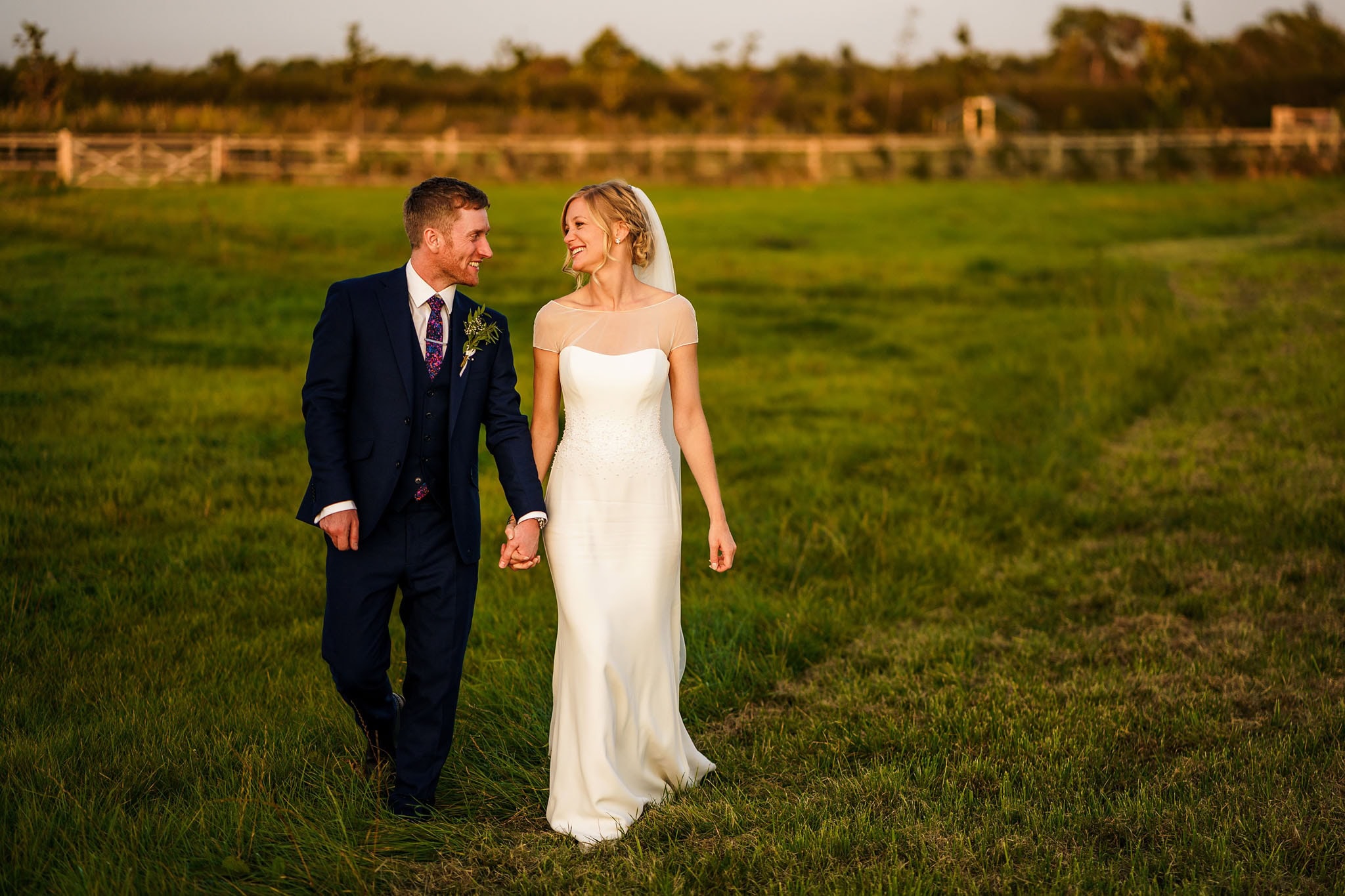 the happy couple walking through a field together