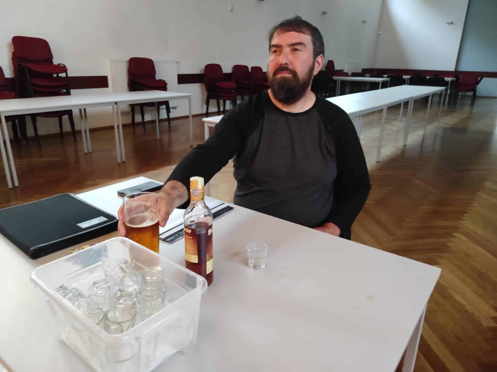 Martin Volf na strašně režie před jevištěm. Sedí u stolu s pivem a flaškou rumu před sebou.