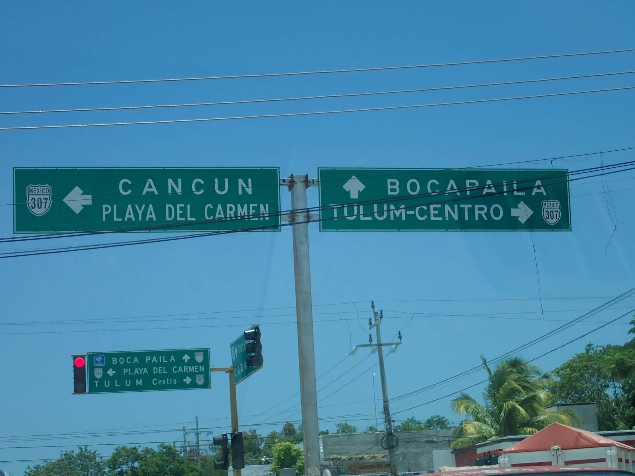 Our Two-Night Stay at Casa Paraiso, Tulum, Mexico 1 Two over head Street signs.The sign to the left reads Cancun and Playa del Carmen. The right sign reads Bocapaila and Tulum-Centro. There are other signs, and electrical wires.