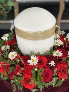 Urnenkranz in rot mit rosen, gerbera und weißer kamile - weiße urne für christliche beerdigung in paffenhofen ilm