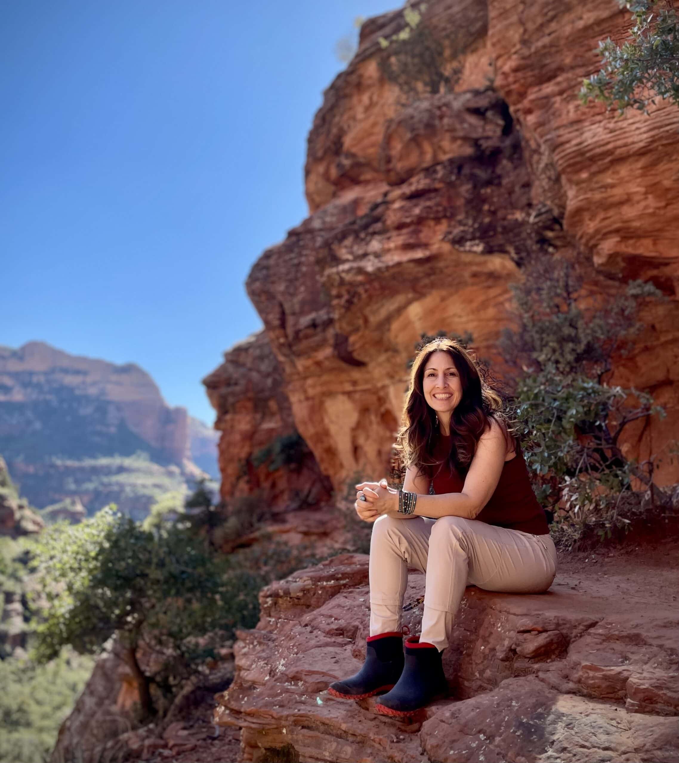 Jodi Aman sitting in front of a cave in Sedona Arizona