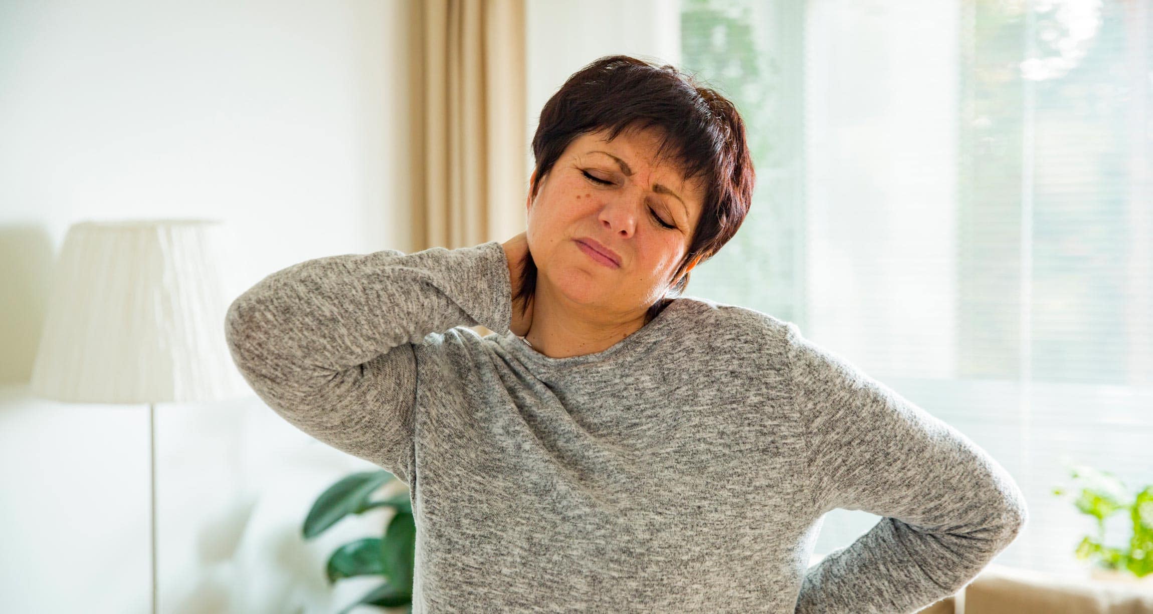 woman holding neck with pained expression