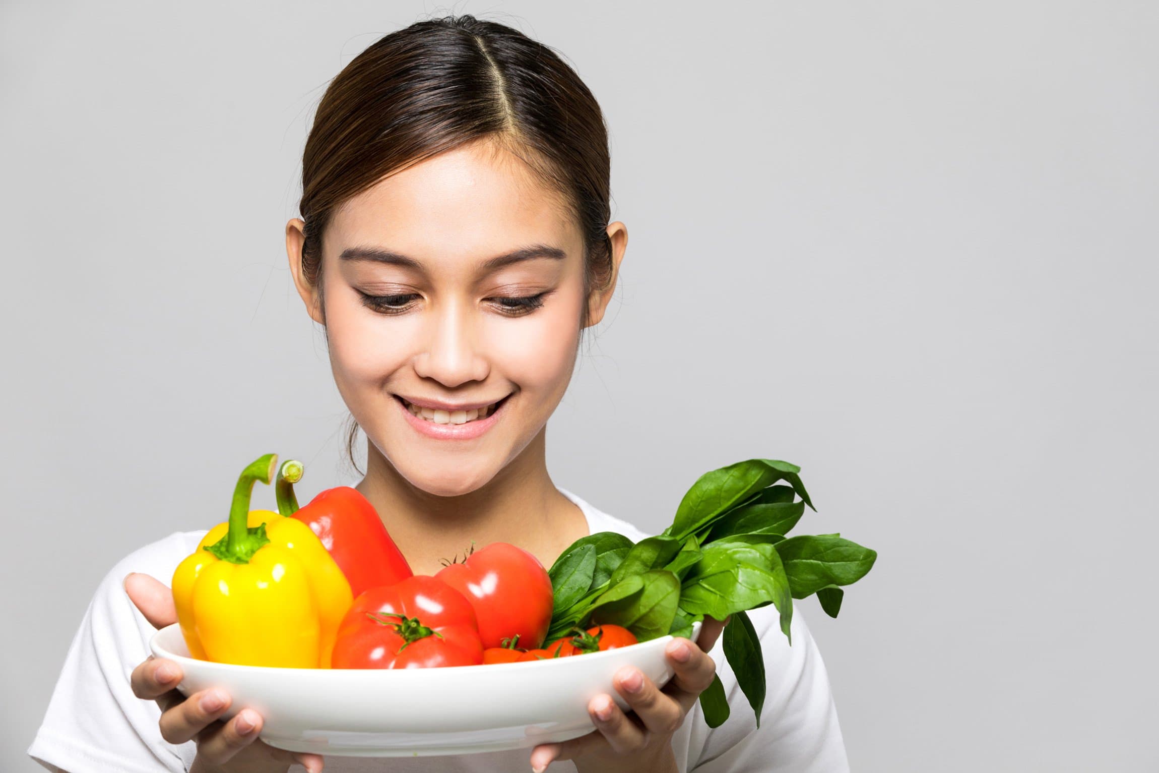 A young girl holding a plate of vegetables