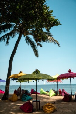 Šareni suncobrani i vreće za sedenje na plaži ispod palme uz more