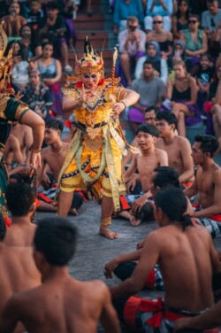 Plesač u žutom kostimu i kruni izvodi kecak pred horom muškaraca