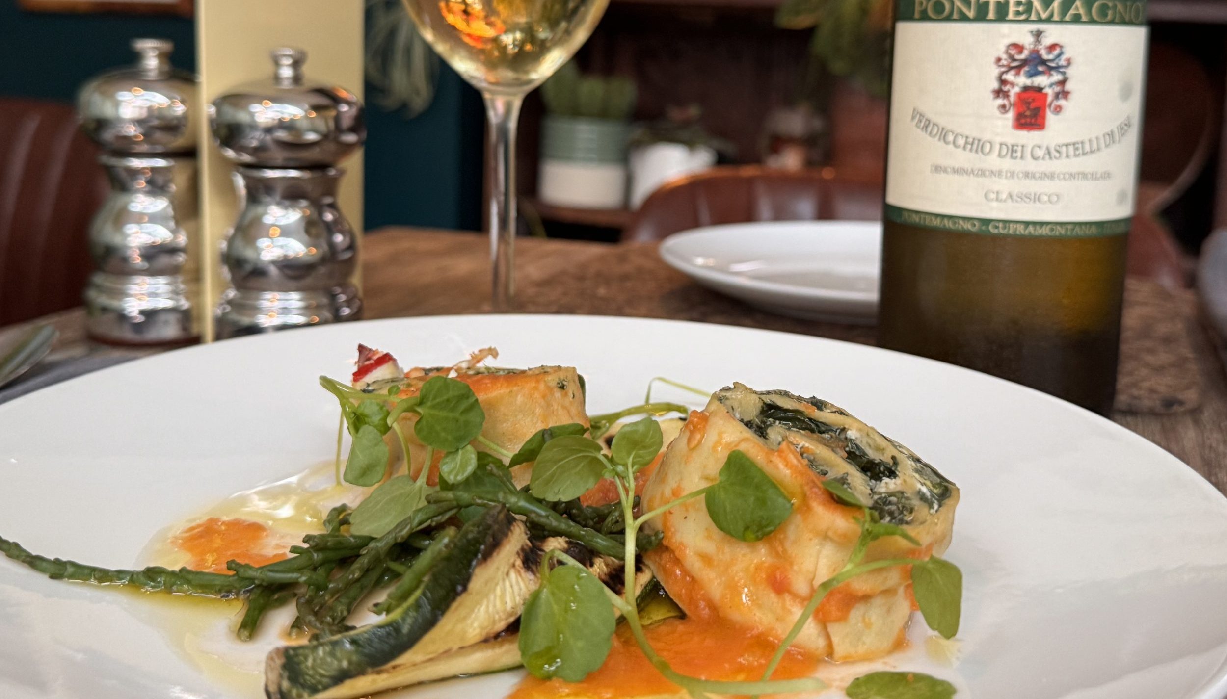 Fine dining pasta with spinach, microgreens, and a glass of white wine.