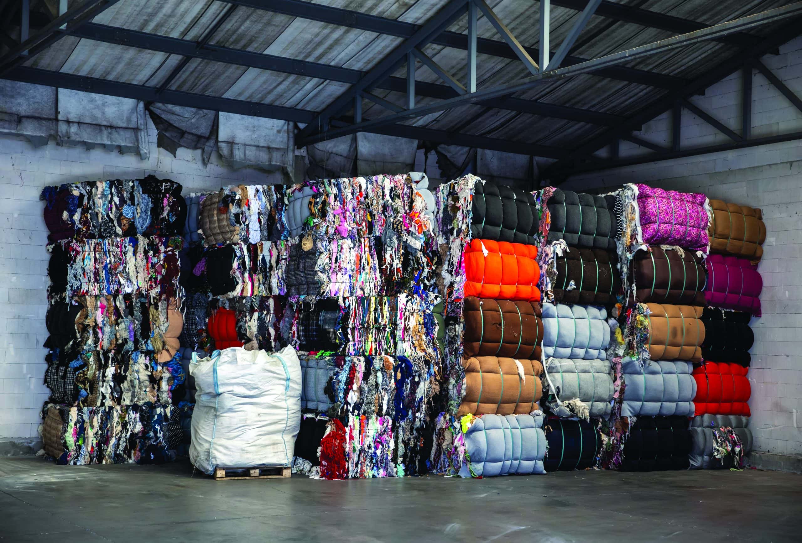 Heap of pressed colorful textile waste packed in bales in store-house