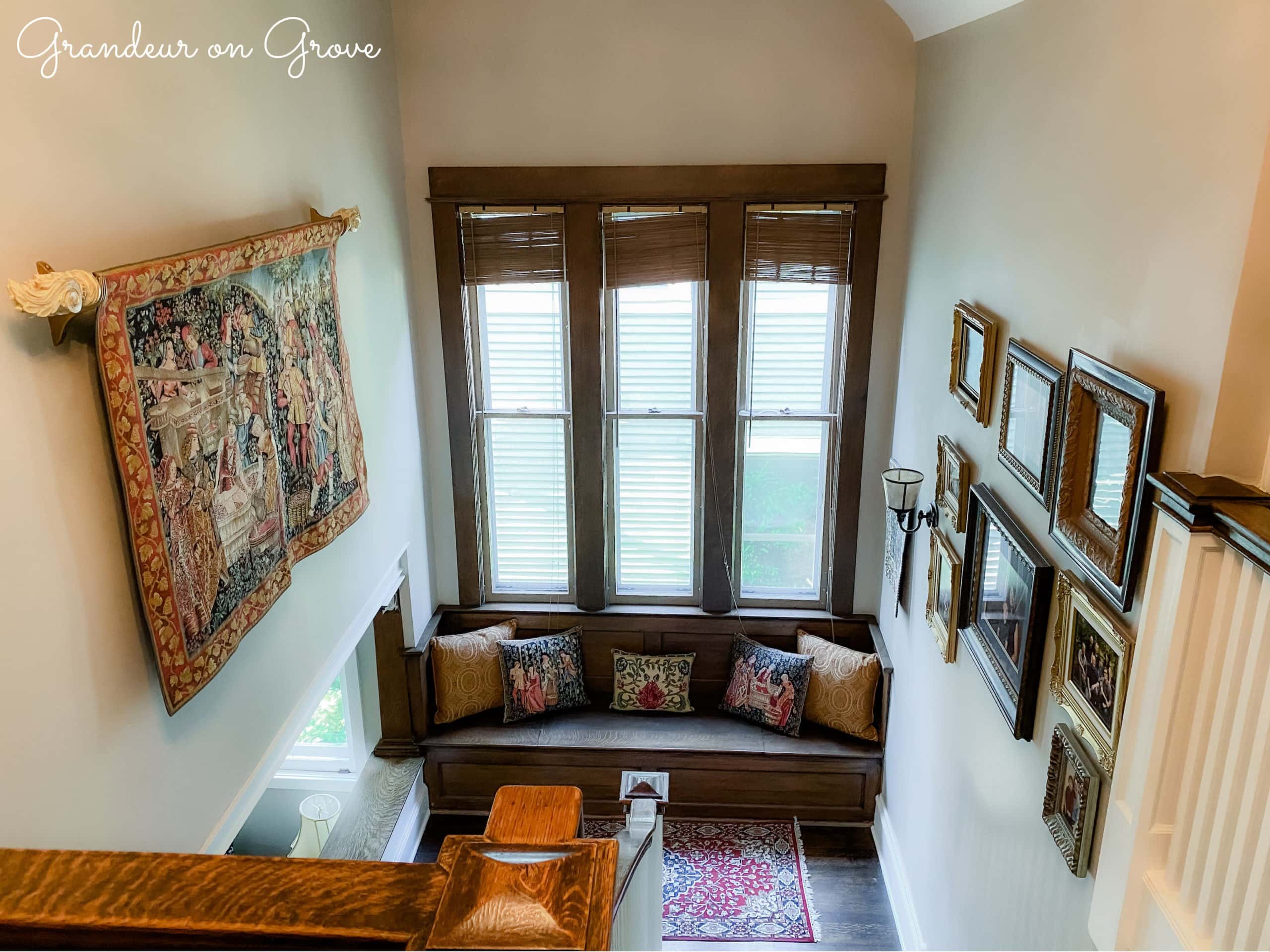 A stairway with hung pictures and tapestries and a bench