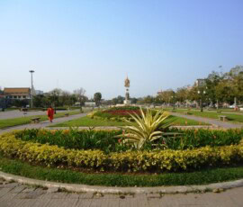 Uređeni gradski park sa cvetnim lejama i spomenikom u pozadini
