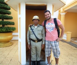 Turista se fotografiše sa naoružanim stražarom ispred žute kapije sa stubovima
