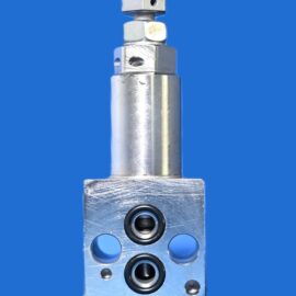 Close-up of a metallic hydraulic valve block with several round ports and a protruding rod against a solid blue background of the image's background space.