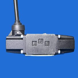 Close-up of a grey industrial coupling block with a vertical rod and stamped A, B, P on a blue background.