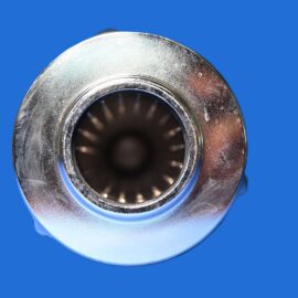 Close-up of a shiny metal bearing or circular mechanical component against a solid blue background, showing inner rings and ridged interior.