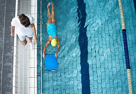 A Swim instructor teaching a child to swim