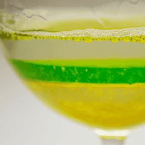 glass showing density with clear, green and yellow liquids