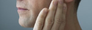 man with hand on jaw