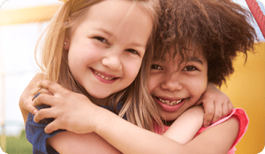 Two preschool girls hugging