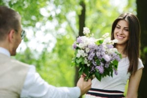 portrait of a man hiding a flowers bouquet behind his back to surprise to a female SKo5qV6rs