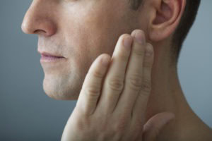 man with hand on jaw