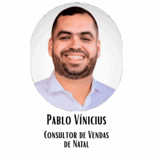 Homem sorridente com barba e cabelo curto, usando camisa social clara, em fundo neutro, representando profissionalismo e confiança.