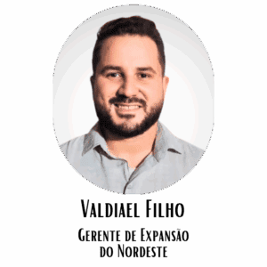 Homem sorridente com barba e camisa cinza claro, retrato profissional para perfil.
