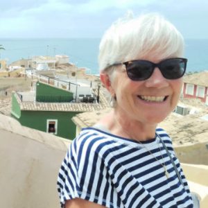 woman stands on rooftop with Med sea in background