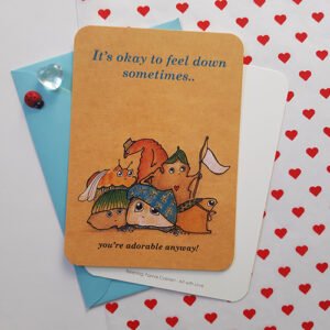 ansichtkaartje met crazy creatures die zich miserabel voelen. met de tekst it's okay to feel down sometimes, you're adorable anyway