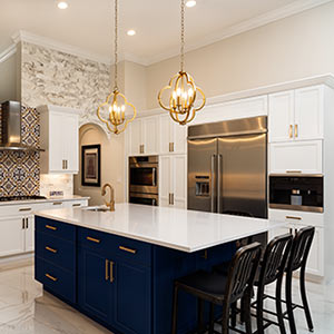 white kitchen with navy island and brass hardware