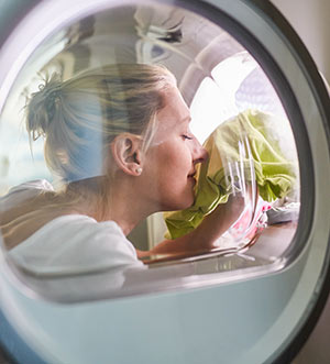woman testing smell of clothes in dryer
