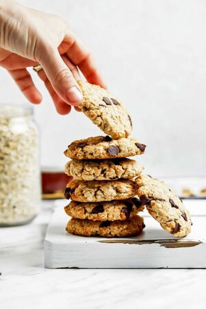 Hand taking a gluten free vegan oatmeal cookie from a stack