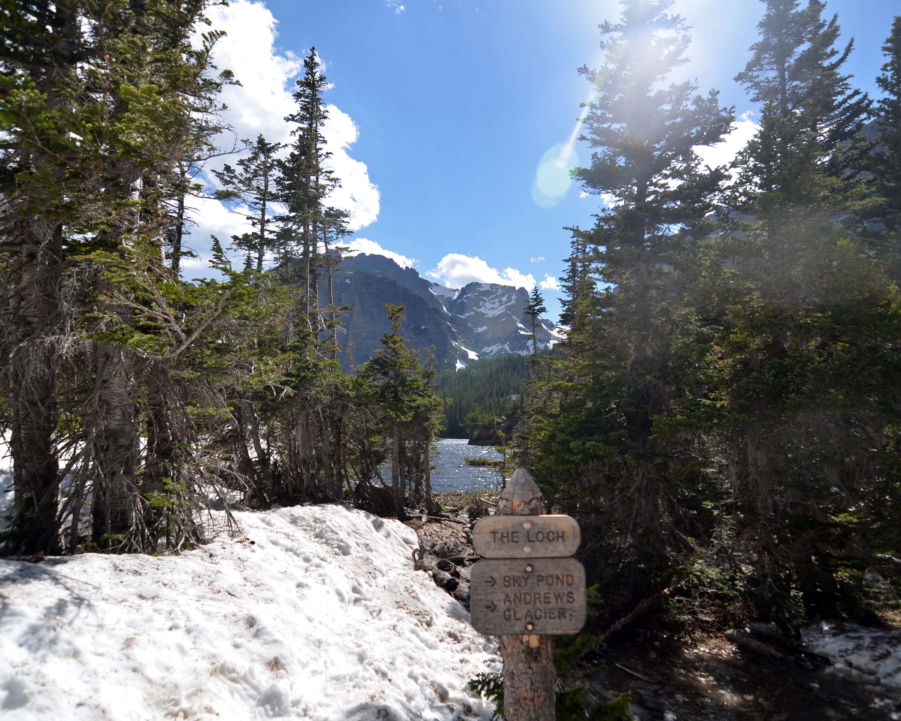 Sign showing The Loch, with the Loch in the background and snow on the ground.