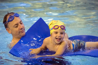 toddler learning to swim with her dad