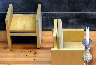 Le fauteuil pour le prêtre et le tabouret pour le chantre. Le style est très épuré, témoin du 20 ème siécle et des écoles architecturales du bauhaus ou du Corbusier.