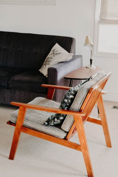 low profile couch and wooden chair with small lamp on side table